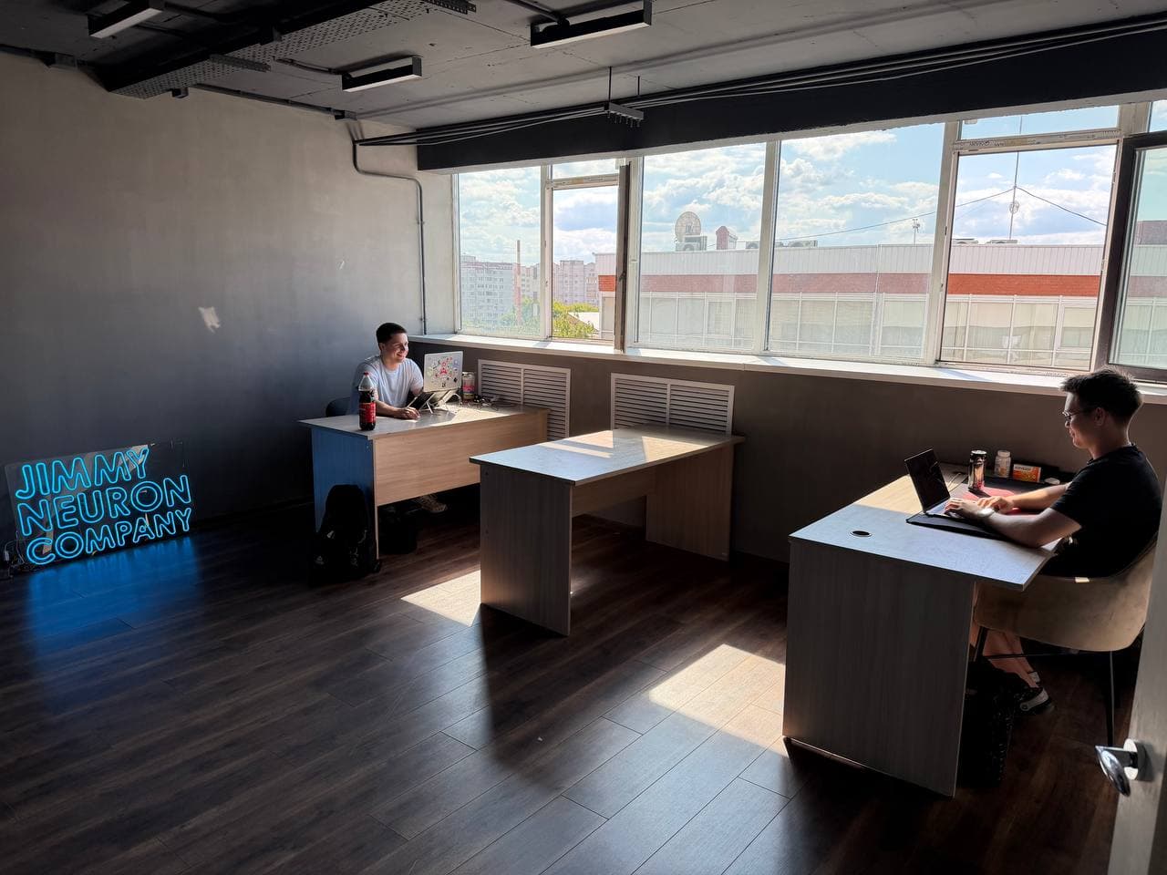 JimmyNeuron office in Kazan: workspace by the window and a Jimmy Neuron Company neon sign