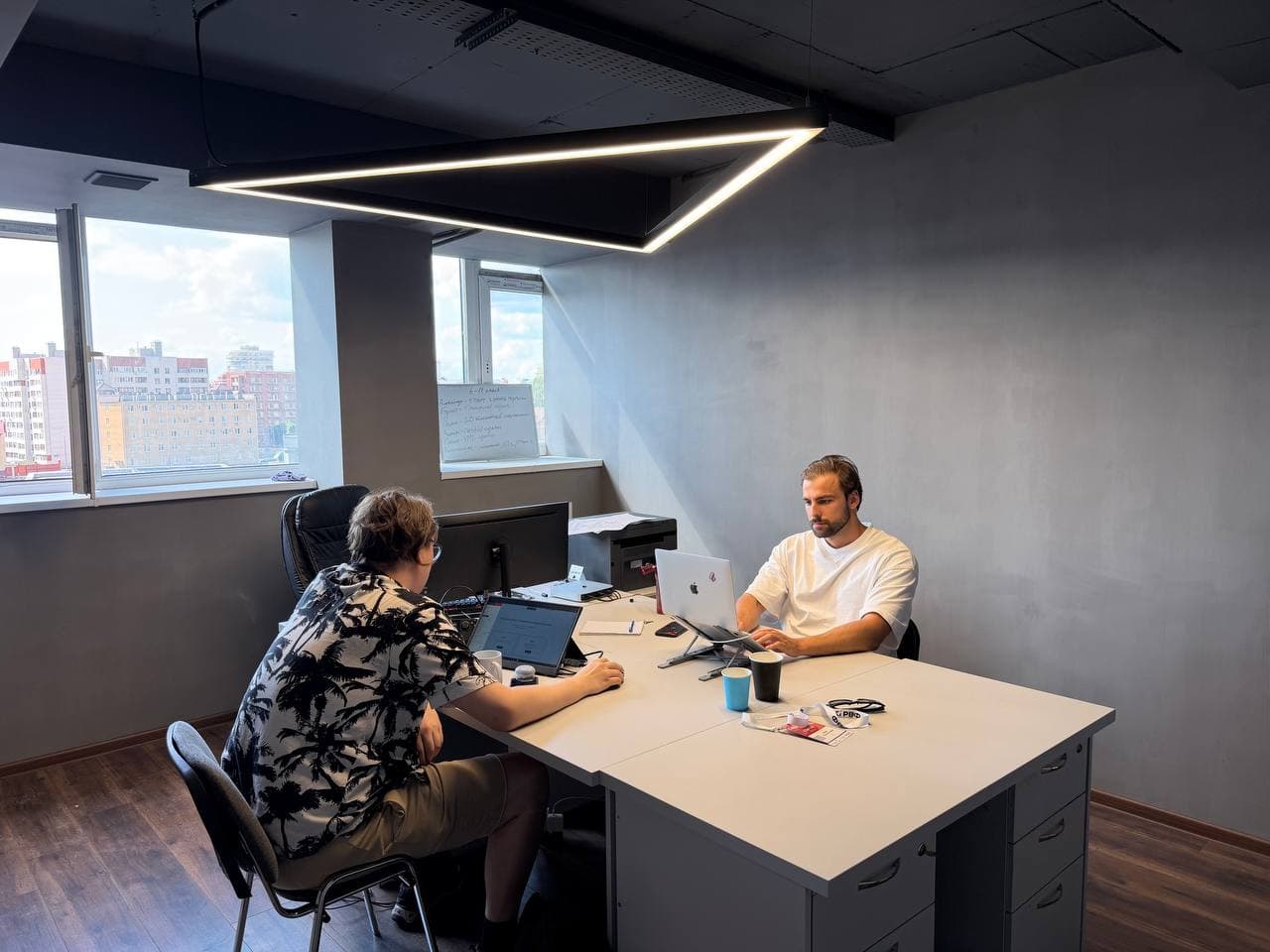 JimmyNeuron office: collaborative work at a shared desk with a city view
